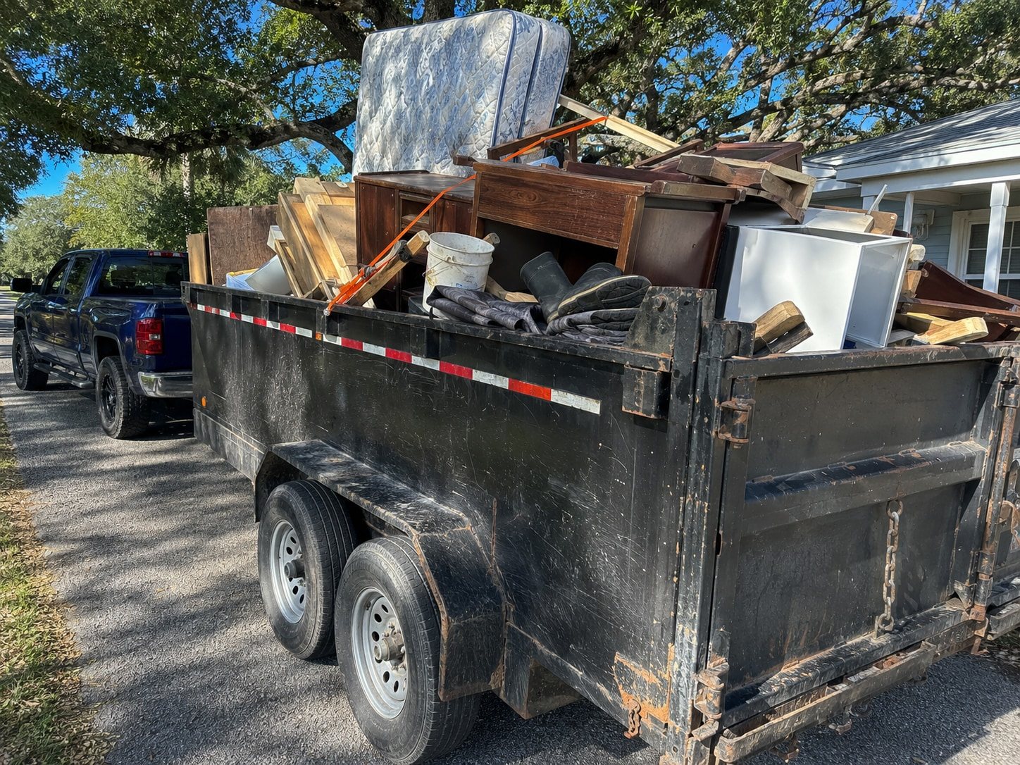 Loaded black dump trailer stacked with household junk
