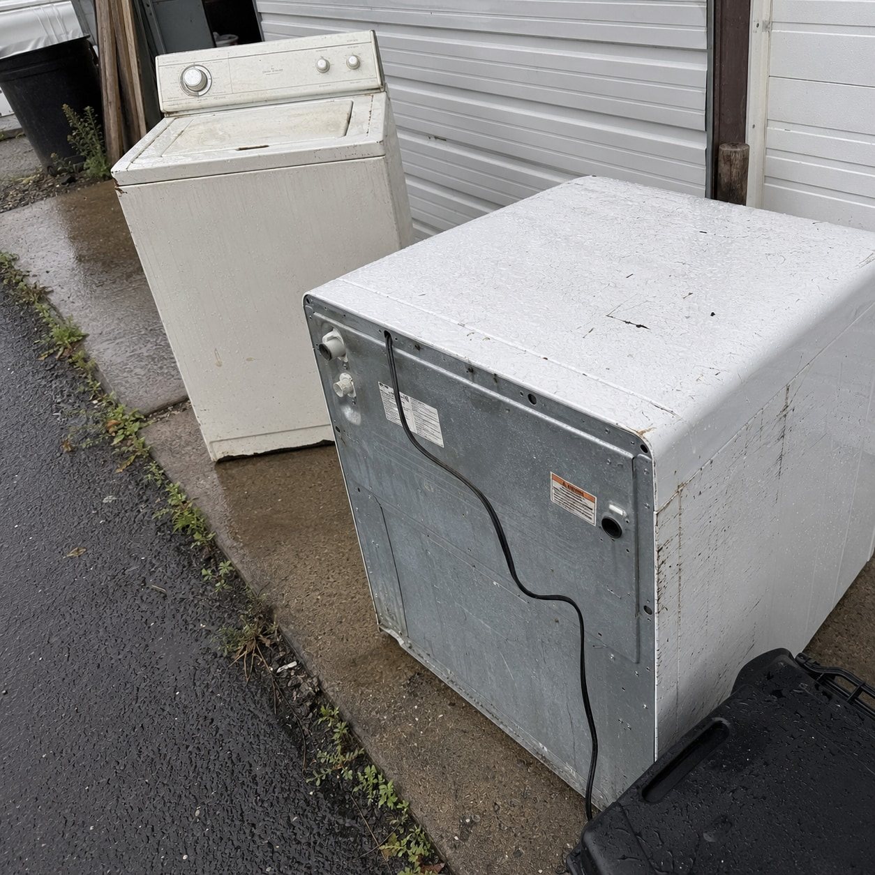 Old dryer sitting on a driveway for pickup
