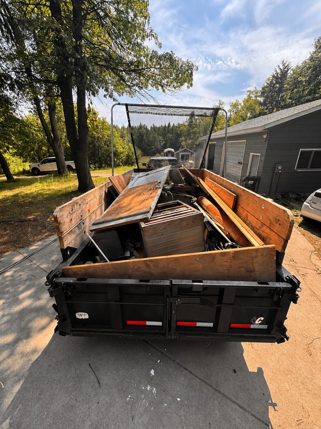 Loaded dump trailer stacked with junk in a driveway
