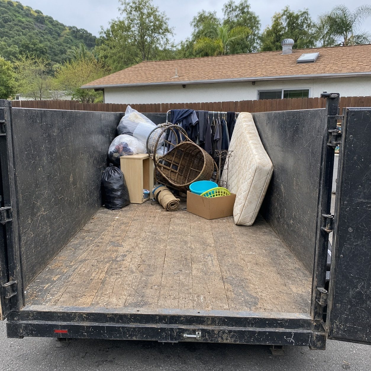 Open utility trailer filled with garage clutter