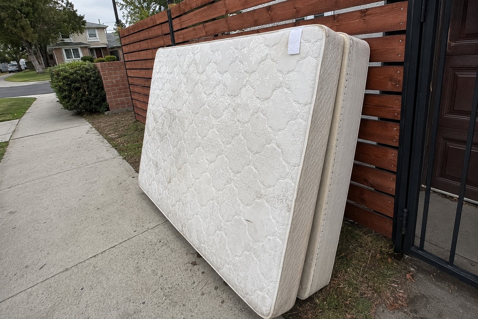 Mattress and box spring leaning against a wall for disposal